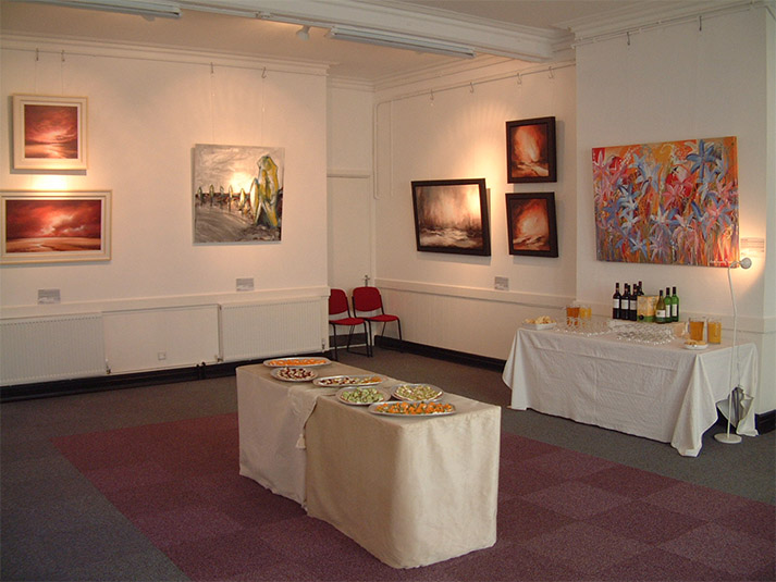 exhibition of paintings and a table of food in a spacious room